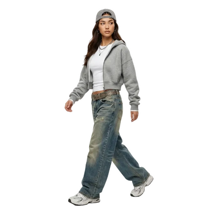 Model wearing a grey cropped zip-up hoodie over a white top with baggy vintage wash denim jeans for a Y2K streetwear look.