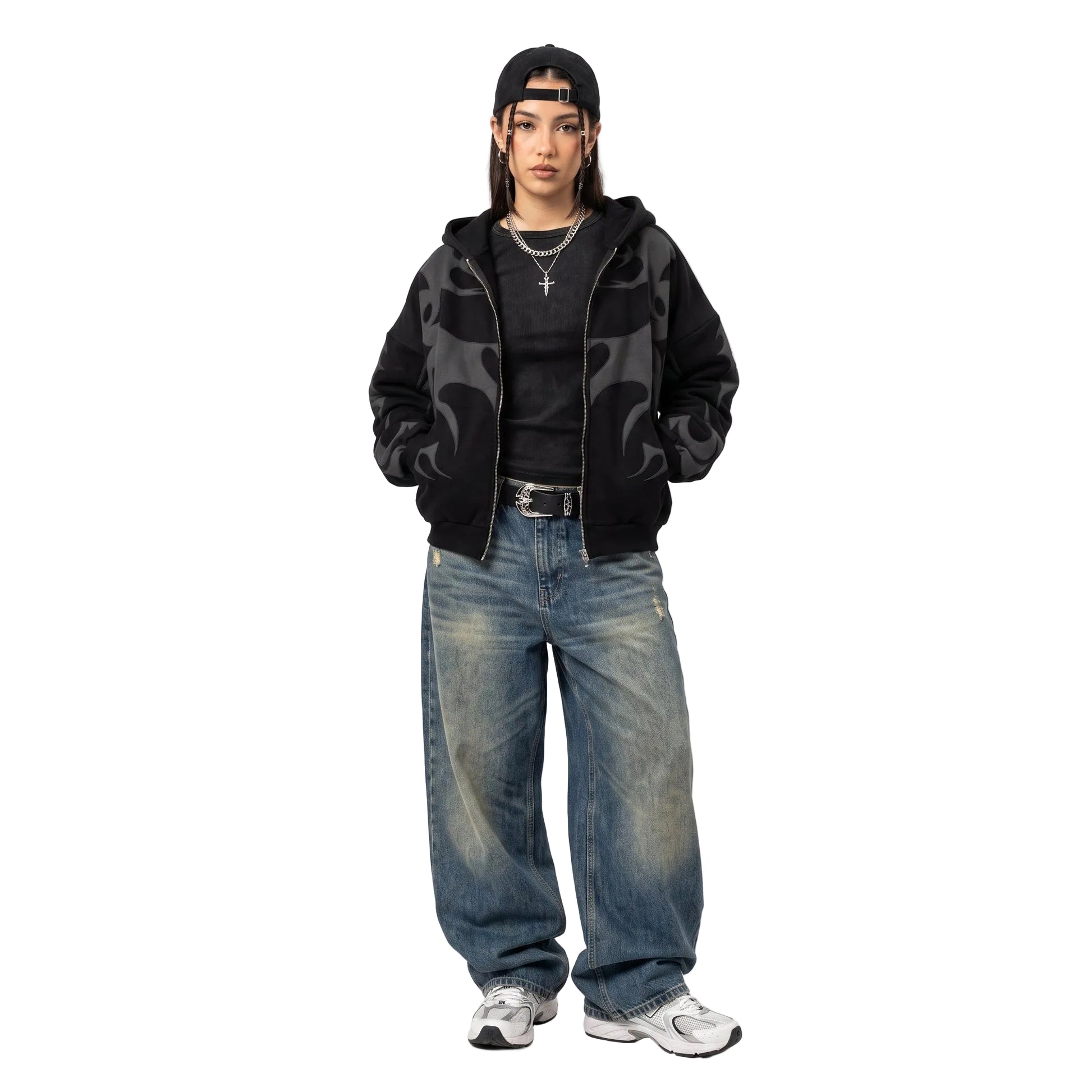 A model posing in a black graphic zip hoodie and baggy vintage wash denim jeans with a belt for a Y2K streetwear look.